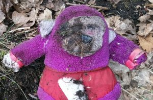 close up of a discarded filthy toy, a purple and grey monkey