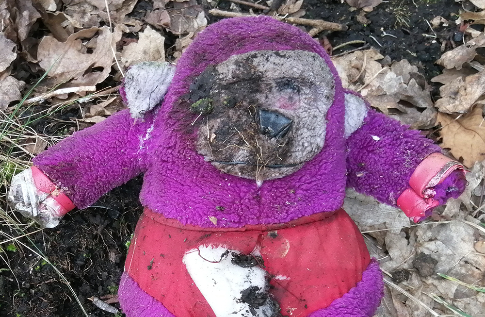 close up of a discarded filthy toy, a purple and grey monkey