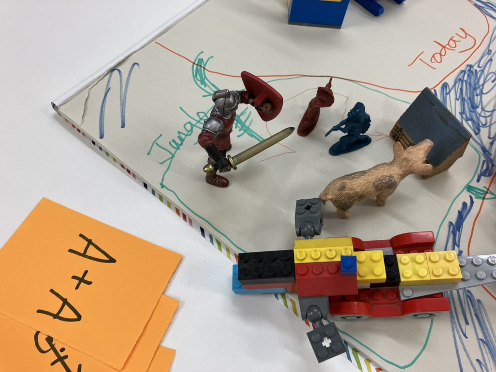 detail of a prototype board game made of paper, toy knights and animals and LEGO