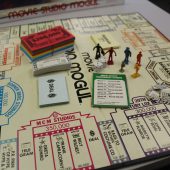 Game board featuring movie studio / business theme, with paper money and plastic figures