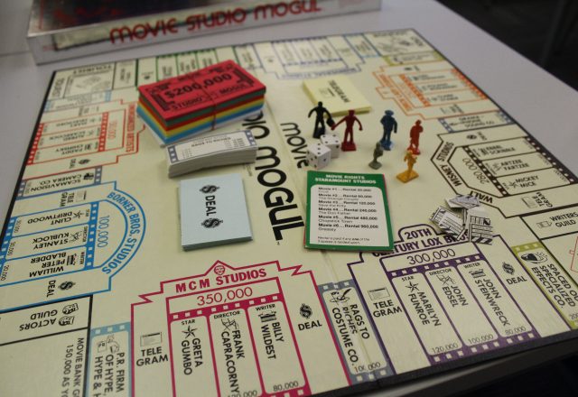 Game board featuring movie studio / business theme, with paper money and plastic figures