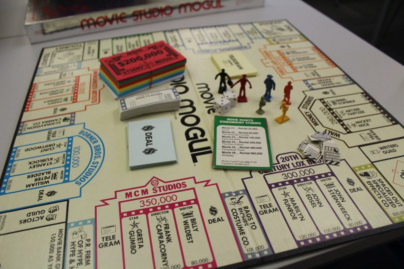 Game board featuring movie studio / business theme, with paper money and plastic figures