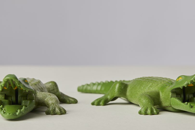 Two Playmobil toy crocodiles in green plastic. Their jointed mouths are open.