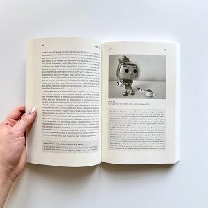 My book Toy Theory, held open at a page featuring an image of a Pop doll version of Buzz Lightyear as 'Mrs Nesbit' in Toy Story.
