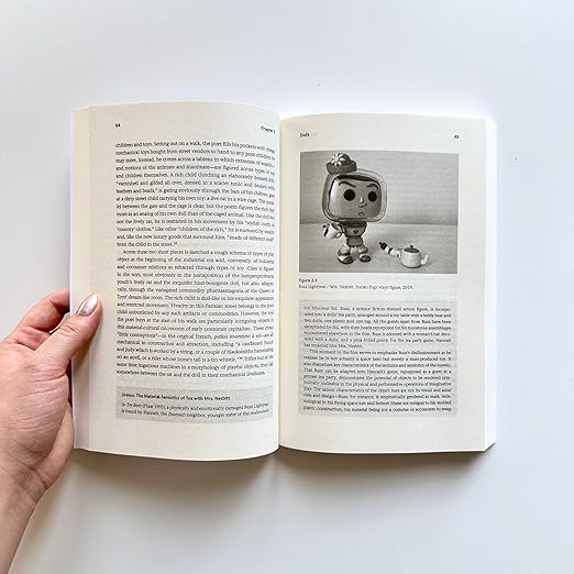 My book Toy Theory, held open at a page featuring an image of a Pop doll version of Buzz Lightyear as 'Mrs Nesbit' in Toy Story.