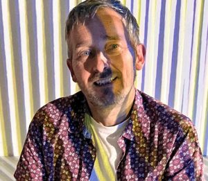 portrait photograph of Seth with bands of coloured light projected over him